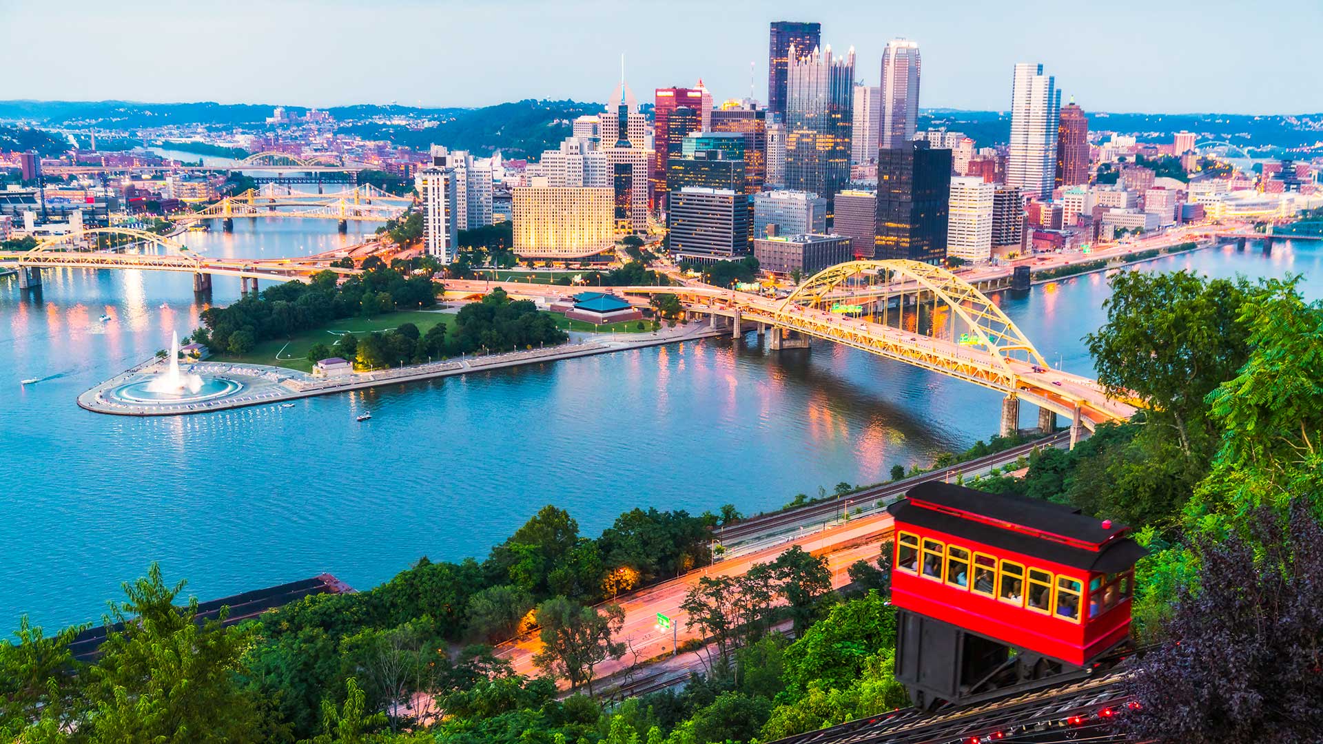 Pittsburgh skyline and bridge overlooking the river at sunset.